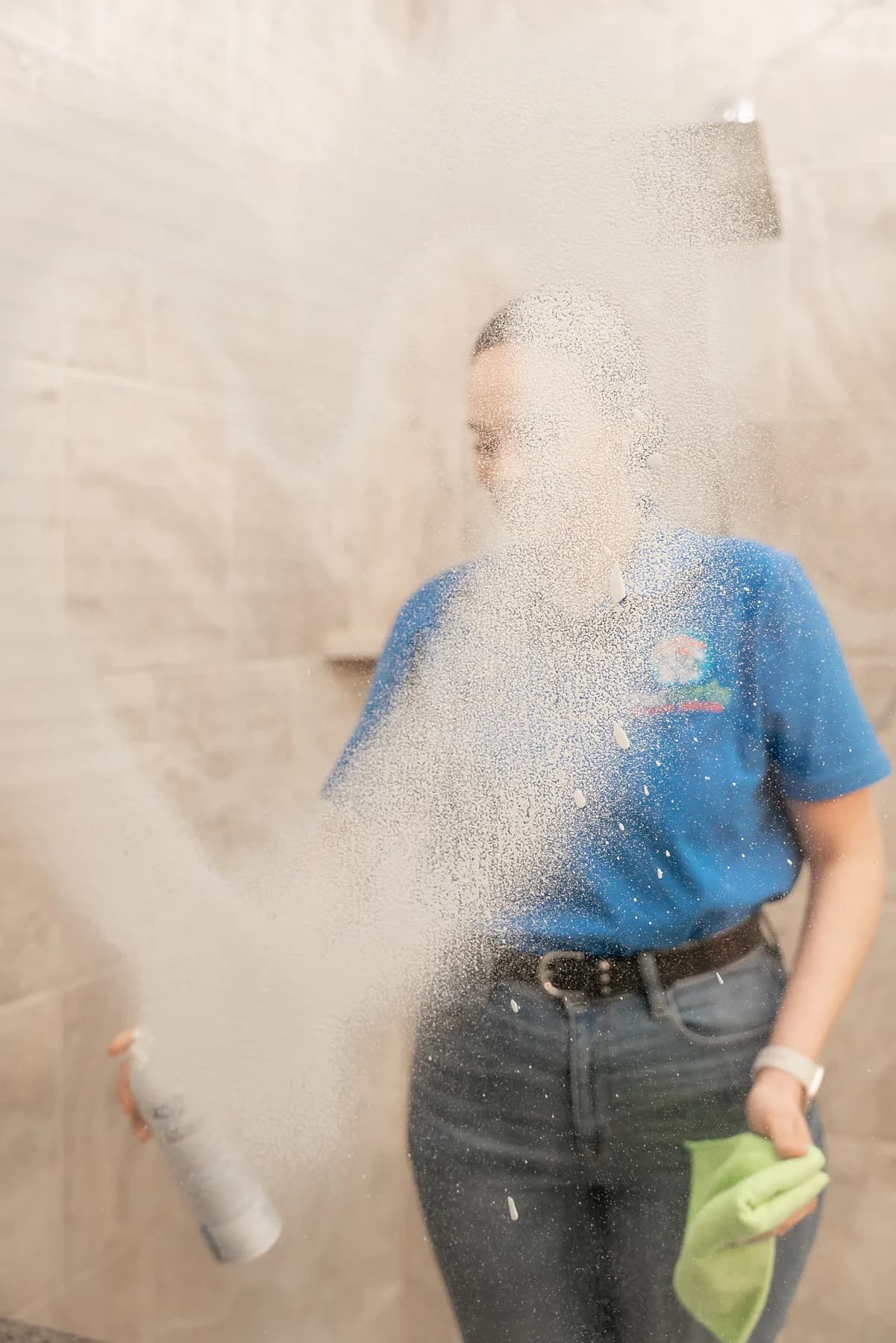 Cleaner cleaning a tiled shower and glass door