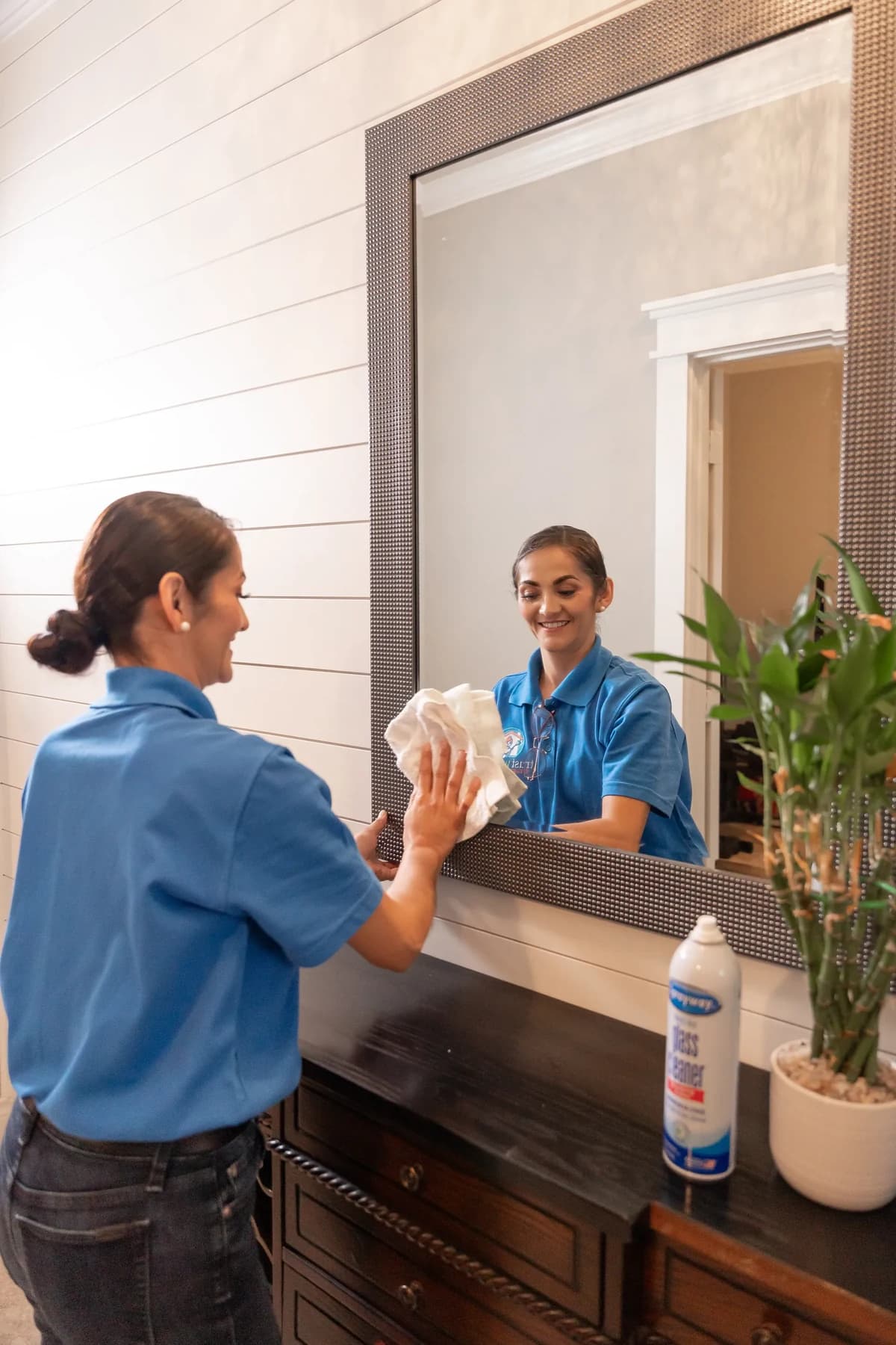 Cleaner polishing an entryway mirror until it is streak free