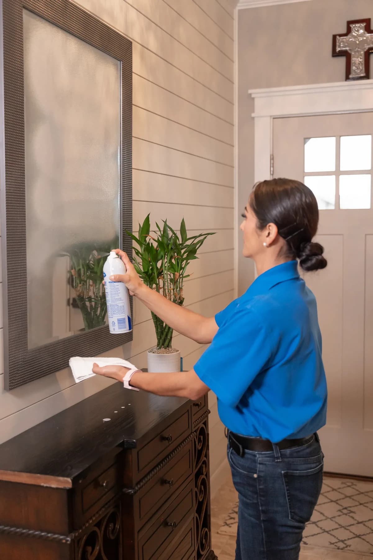 Cleaner polishing an entryway mirror until it is streak free