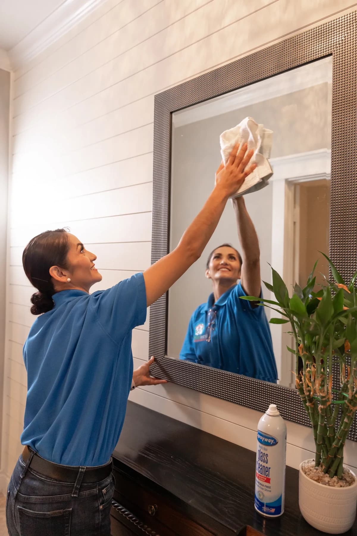 Cleaner polishing an entryway mirror until it is streak free