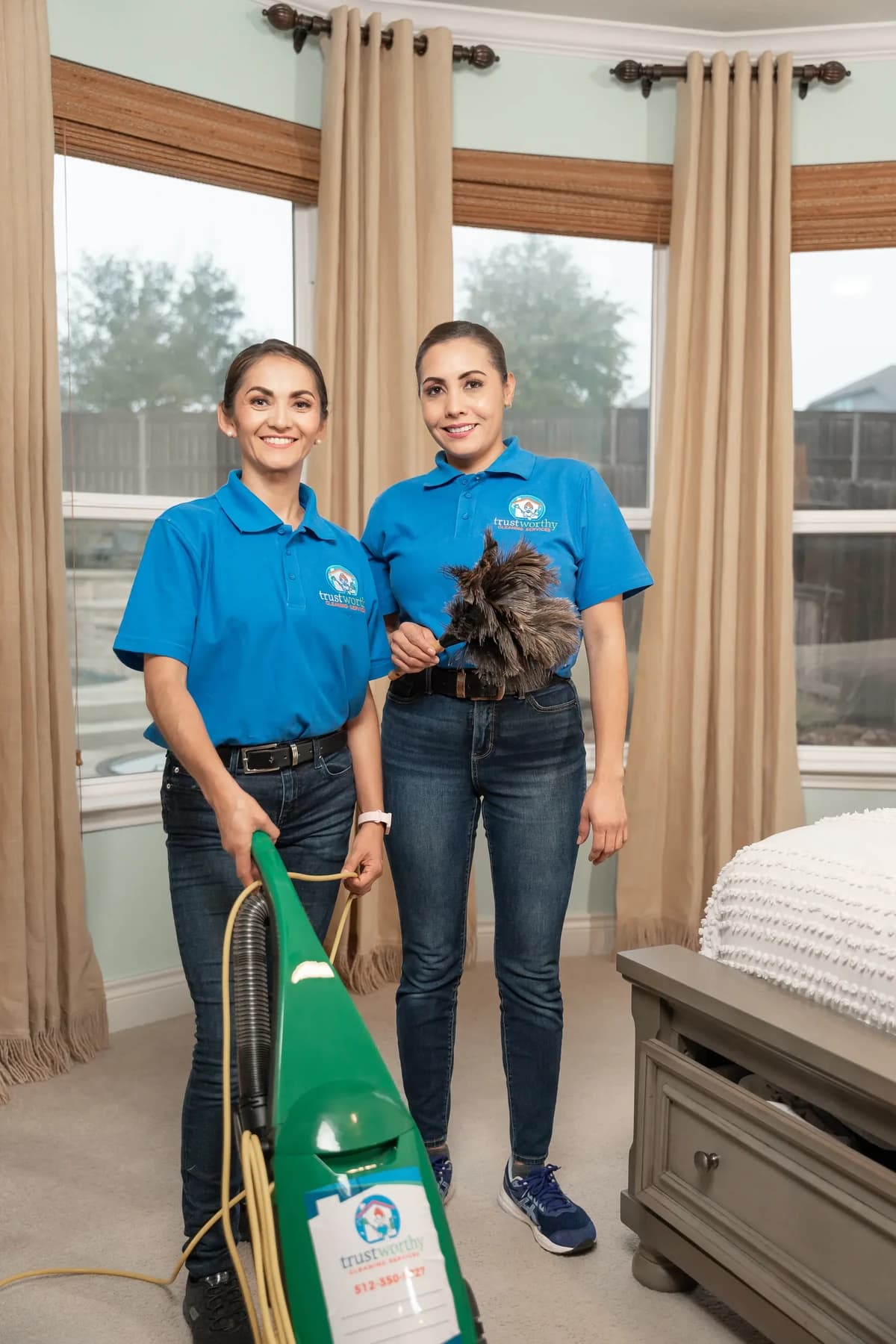 Cleaner dusting bedroom window sills and vacuuming the floor