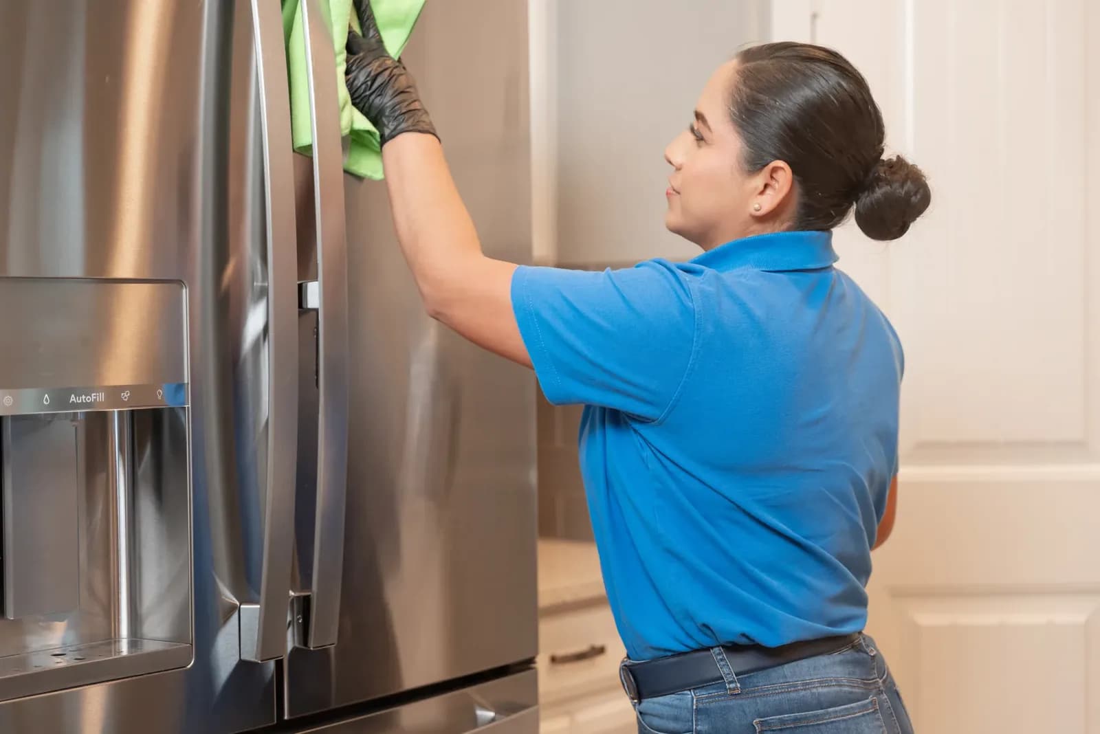 A Trustworthy cleaner wiping down a stainless steel refrigerator in Austin, TX