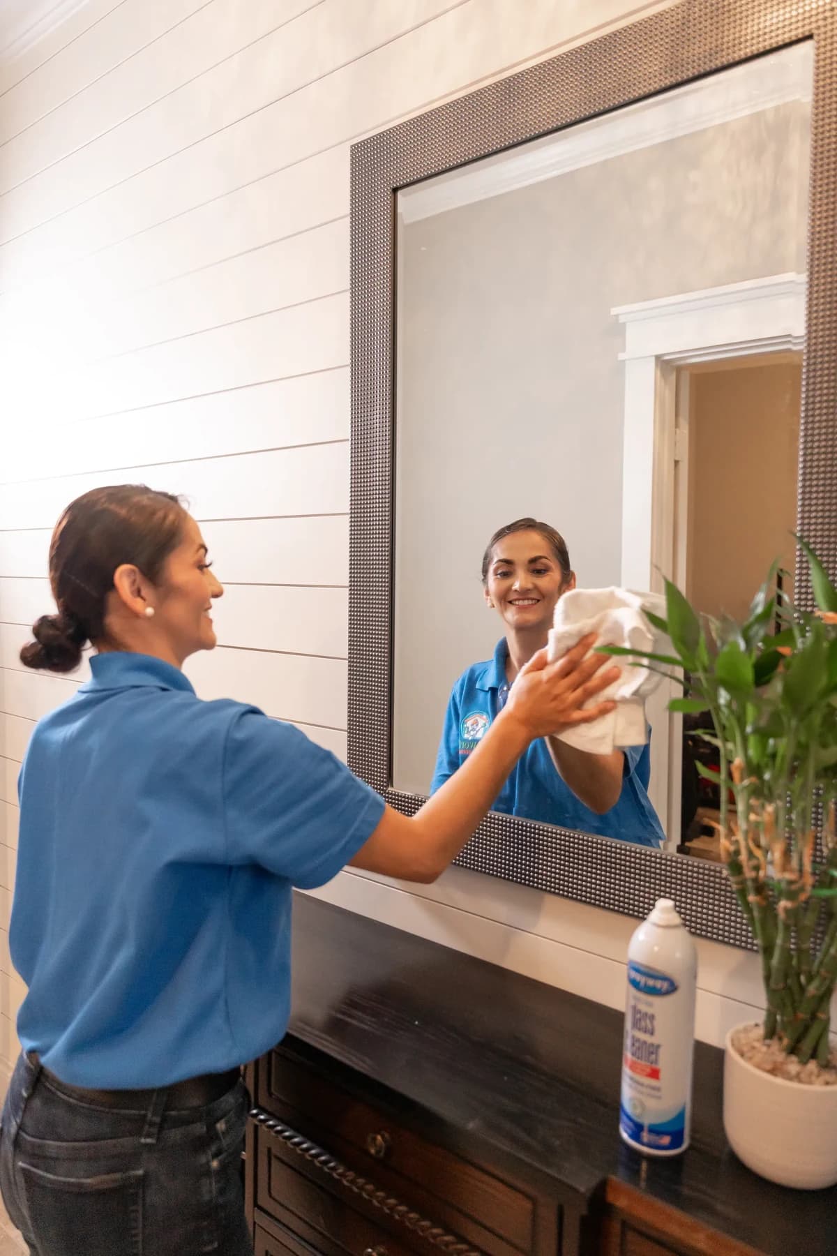 Cleaner polishing an entryway mirror until it is streak free