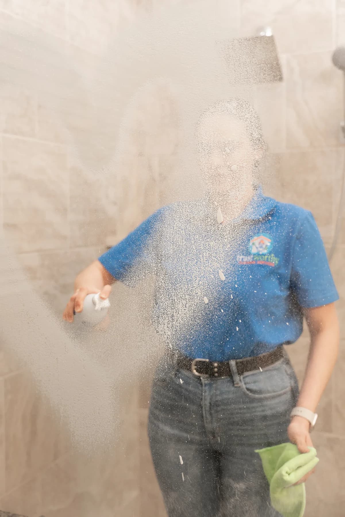 Cleaner cleaning a tiled shower and glass door
