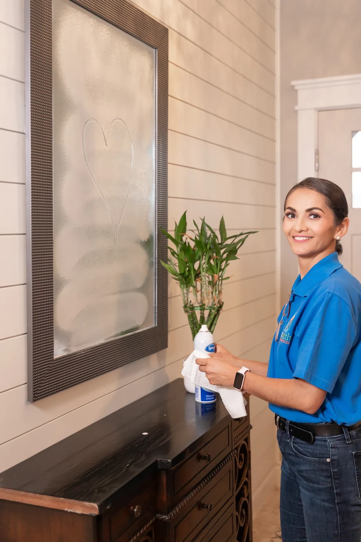Cleaner polishing an entryway mirror until it is streak free
