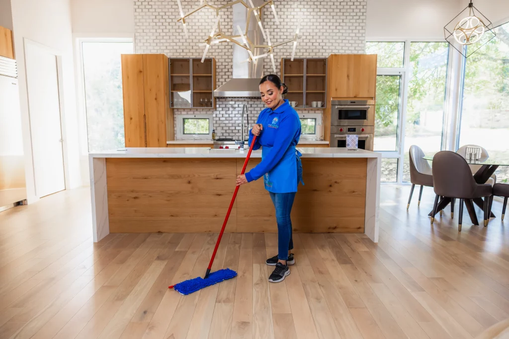Trustworthy Cleaning Services team member mopping a hardwood floor in a large open space during a commercial cleaning in Austin, Texas