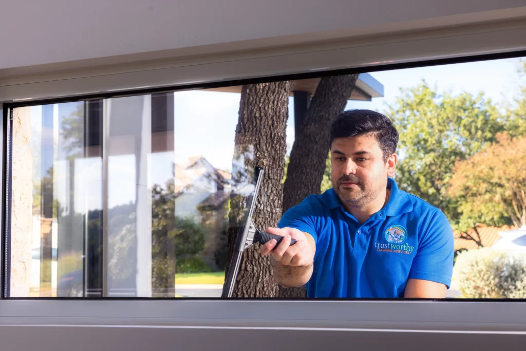 Trustworthy Cleaning Services technician squeegeeing a floor-to-ceiling window pane during a commercial window cleaning in Austin, Texas